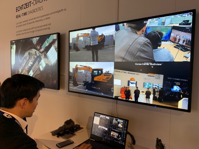 SK텔레콤과 현대건설, 현대건설기계 관계자들이 이달 초 독일 ‘바우마 2019’전시회에서 실시간 영상 관제 솔루션 ‘T 라이브 캐스터’를 활용한 국가간 건설현장 원격 모니터링 시연을 선보였다. 사진은 충청남도 서산 건설현장의 드론 영상을 분당 현대건설기계 사옥(사진1)과 독일 뮌헨의 전시관(사진2)으로 실시간 전송하는 모습. / 사진 제공 = SK텔레콤