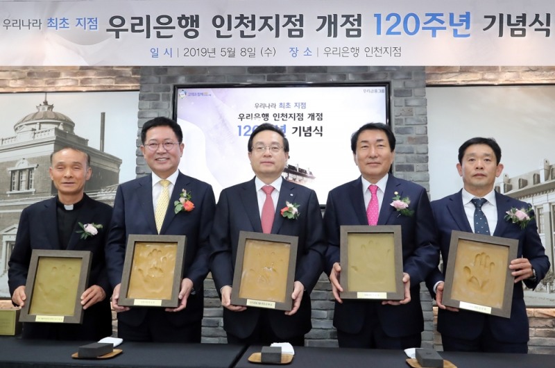 우리은행은 지난 8일 인천지점에서 ‘인천지점 개점 120주년 기념행사’를 실시했다. 개점 행사에 참석한 주요인사들이 인천지점의 새로운 출발과 힘찬 도약을 다짐하는 의미에서 본인의 핸드프린팅을 들고 기념사진을 촬영하고 있다. (왼쪽부터 이용권 카톨릭아동청소년재단 이사장(신부), 박남춘 인천시장, 손태승 우리금융그룹회장 겸 우리은행장, 안상수 국회의원, 김영제 ㈜NKG 대표이사) / 사진 제공 = 우리은행