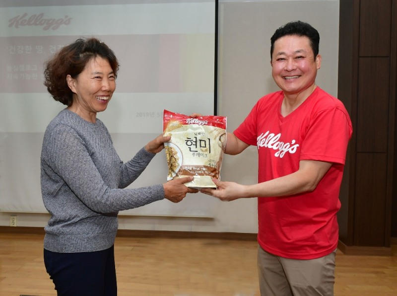 농심켈로그 김종우 대표이사(오른쪽)가 충남 서천군 현미농가 안춘숙 대표(왼쪽)에게 서천 현미 농가에서 수확한 현미로 만든 켈로그 고소한 현미그래놀라를 선물하며 기념촬영을 하고 있다.