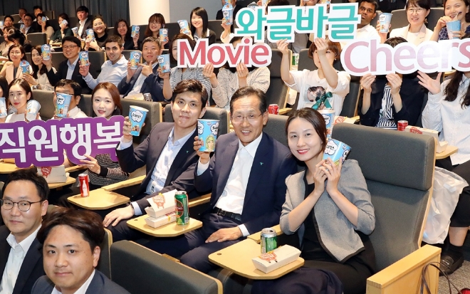 KEB하나은행은 28일 저녁 을지로 신축본점 대강당에서 직원들의 행복과 소통을 위한 시네마 데이 행사 "와글바글 무비 치어스"를 개최했다.이 날 깜짝 방문해 직원들과 영화를 함께 보며 격의 없이 소통하는 시간을 가진 지성규 KEB하나은행장(사진 앞에서 두번째 줄 오른쪽에서 두번째)이 직원들과 함께 팝콘을 들고 기념촬영을 하고 있다. / 사진 제공 = KEB하나은행