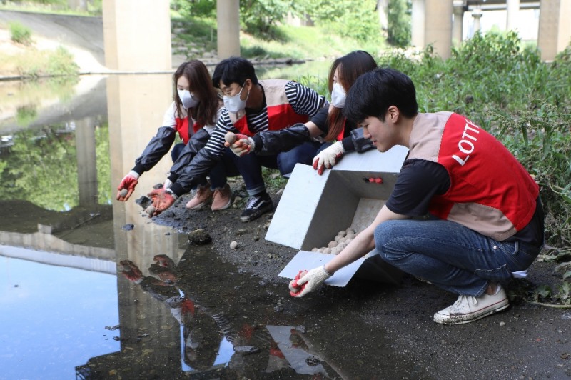 11일, 서울시 서초구 반포동의 반포천에서 롯데백화점 본사 및 4개 대형점포 소속의 샤롯데 봉사단원 100여 명이 'EM 흙공 만들기 및 던지기' 봉사활동을 진행하는 모습. (사진=롯데쇼핑)