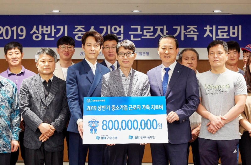 12일 을지로 기업은행 본점에서 김도진 은행장(앞줄 오른쪽 두 번째)과 이정재 홍보모델(앞줄 왼쪽 두 번째), 중소기업 근로자 가족들이 치료비 전달식을 마치고 기념촬영을 하고 있다.