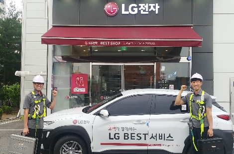 LG전자 서비스 엔지니어가 에어컨 실외기 등을 수리시 사용하는 보호구를 착용하고 신규 공급차량 앞에서 포즈를 취하고 있다. 사진=LG전자