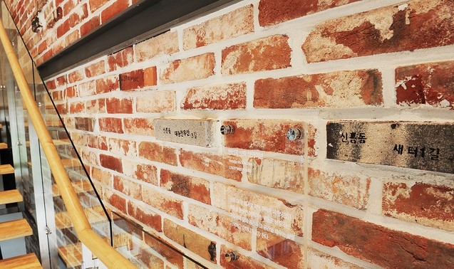 대전 신흥3 재개발구역 내 담장에 사용됐던 벽돌로 꾸민 신흘 SK뷰 견본주택 내부 계단 측벽의 모습. (SK건설 제공)