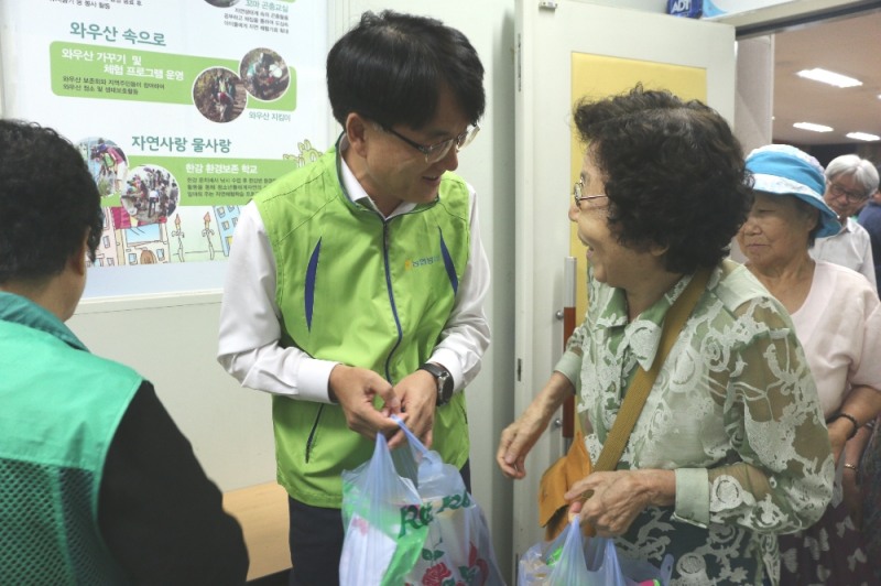 7일, 마포구 서강동 주민센터에서 진행된 「건강한 여름나기 삼계탕 나눔 행사」에서 손병환 농협금융 사업전략부문장(상무)(사진 왼쪽 두번째)이 지역 어르신에게 삼계탕을 나누어 드리고 있다.