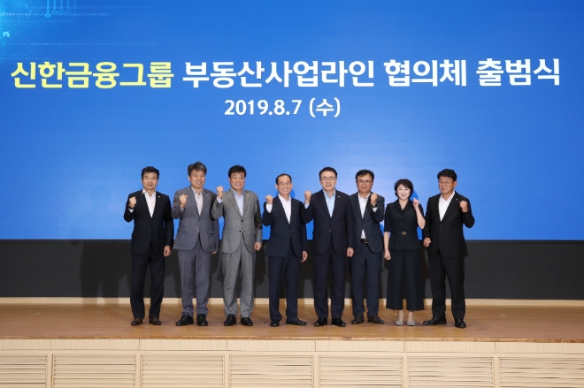 신한금융그룹(회장 조용병)은 7일 서울 세종대로에 위치한 신한지주 본사에서 조용병 회장을 비롯한 지주 경영진, 유관 그룹사 CEO와 사업부문장 등 약 60여 명이 참석한 가운데 '그룹 부동산사업라인 협의체' 출범식을 개최했다. 이날 행사에서 조용병 회장을 비롯한 그룹 경영진들이 기념 촬영을 하고 있다. (사진 왼쪽부터 미래전략연구소 이성용 대표, 신한대체투자운용 김희송 사장, 신한BNPP자산운용 이창구 사장, 아시아신탁 배일규 사장, 신한금융그룹 조용병 회장, 신한리츠운용 남궁훈 사장, 그룹WM사업부문 왕미화 부문장, 그룹GIB사업부문 정운진 부문장) / 사진 제공 = 신한금융그룹