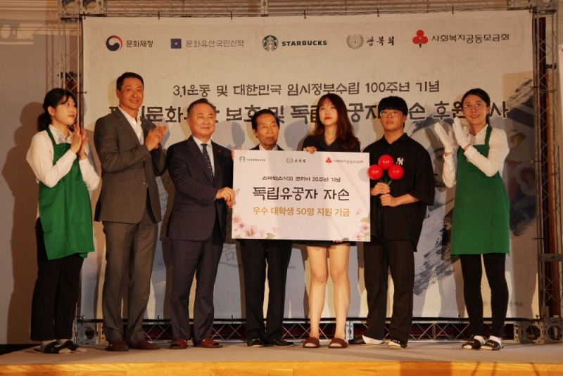 스타벅스가 대한민국 임시정부 설립 100주년 및 광복 74주년을 기념해 8월 13일 덕수궁 중명전에서 독립문화유산 보호 및 독립유공자 자손 장학금 후원 행사를 진행했다. 스타벅스커피 코리아 송호섭 대표이사(왼쪽에서 두 번째)와 사회복지공동모금회 예종석 회장(왼쪽에서 세 번째), 광복회 김복열 이사(왼쪽에서 네 번째)가 독립유공자 양한묵 선생의 고손녀인 양소은 학생(오른쪽에서 세 번째)과 정상복 애국지사의 증손자인 정성재 학생(오른쪽에서 두 번째)에게 독립유공자 자손장학금을 전달하고 있다.
