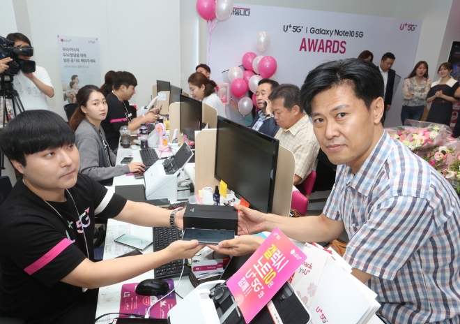 LG유플러스는 20일(화) 오전 서울 종각역직영점에서 삼성전자 갤럭시 노트10 5G 개통을 기념해 고객 감사 행사 ‘U+갤럭시 노트 어워즈’와 ‘이색S펜 사인회’를 진행한다고 밝혔다. 사진은 LG유플러스 종각역직영점에서 열린 삼성전자 '갤럭시 노트10 5G' 출시 행사장에서 고객이 개통된 폰을 전달 받고 있는 모습. /사진 제공 = LG유플러스