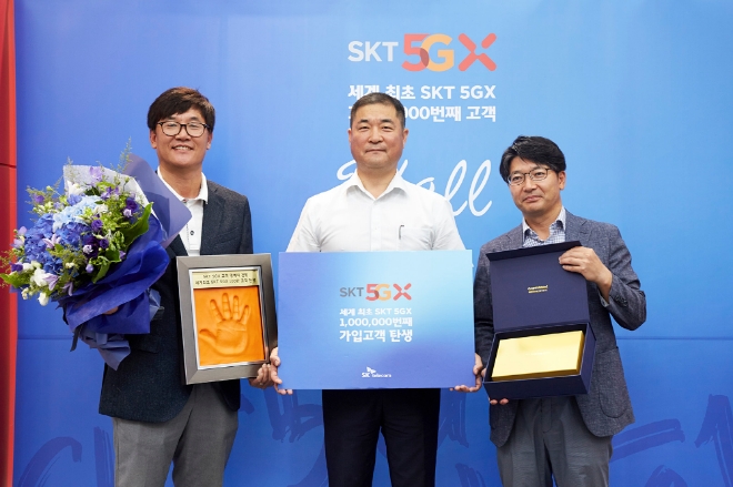 SK텔레콤은 세계 최초 5G 100만 명 돌파를 기념해 100만 번째 5G 고객을 찾아 22일 부산시 해운대구 T월드 대리점에서 축하 행사를 펼쳤다고 밝혔다.(사진 왼쪽부터) SK텔레콤 김성수 영업본부장, 100만번째 고객 이상국 씨, SK텔레콤 임봉호 부산마케팅본부장이 핸드 프린팅과 경품을 들고 포즈를 취하고 있다.