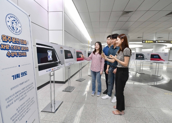 지하철 이용객들이 봉은사역에서 음주운전 타파 차량 스티커 공모전 수상작을 관람하고 있다.