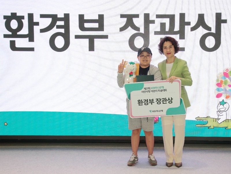 KEB하나은행은 지난 21일 인천 청라에 소재한 하나금융그룹 연수 시설인 ‘하나글로벌캠퍼스’에서 『제 27회 KEB하나은행 자연사랑 어린이 미술대회 본선 및 시상식』을 개최했다. 노유정 KEB하나은행 변화추진본부장(사진 오른쪽)이 대회 대상인 환경부장관상을 수상한 이승재 군(광명 빛가온초등학교 6학년)과 함께 기념촬영을 하고 있다.