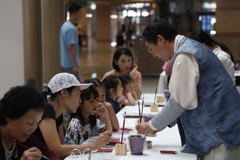 사진=인천공항 제1여객터미널에 마련된 전통공예체험공간에서 무형문화재 제119호 김기호 장인의 도움을 받아 방문객이 금박 책갈피 체험을 진행하고 있다