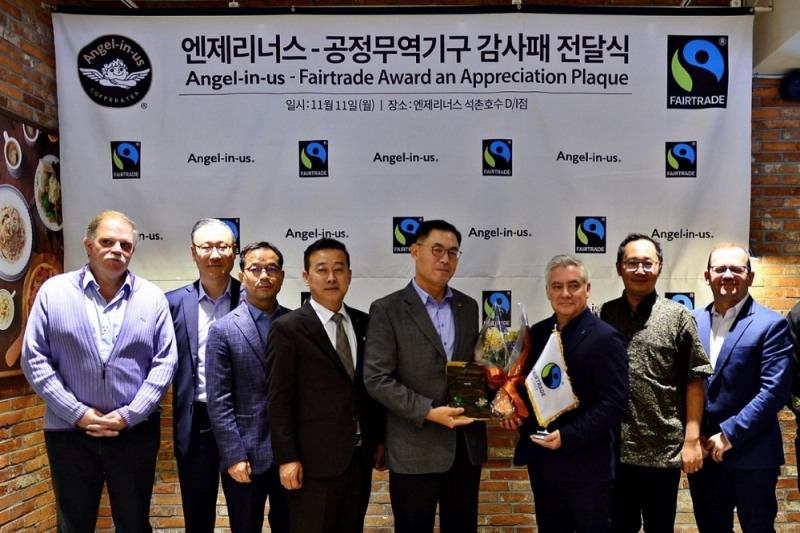 11일 엔제리너스 석촌호수점에서 롯데GRS 남익우 대표(오른쪽 4번째)가 국제 공정무역기구 커피 최고 책임자 피터 캐틀러(Peter Kettler)로부터 감사패를 전달 받고 기념촬영을 하고 있다