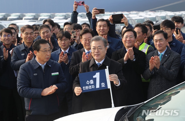 문재인 대통령이 3일 오전 경기 평택시 평택항에서 2020년 친환경차 수출 1호 '니로'에 기념 깃발을 달아주고 있다.