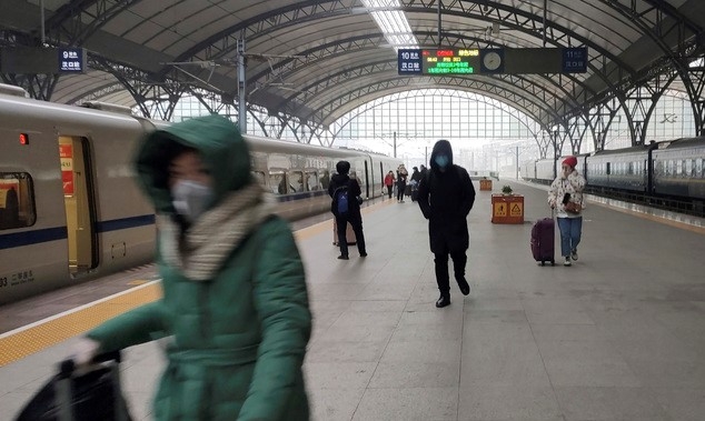 폐렴이 강타한 중국 우한에서 23일 봉쇄령이 내려지기 직전 몇몇 사람들이 기차역 플랫폼에서 마스크를 쓴 채 걸어가고 있다.