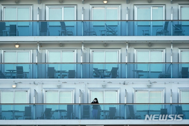 신종 코로나바이러스 감염증 확진자가 무더기로 나온 일본 크루즈선 다이아몬드 프린세스에서 지난 6일 마스크를 쓴 승객이 테라스에 나와 밖을 내다보고 있다. 이 크루즈선은 현재 요코하마에 정박해있으며, 승객들은 하선을 하지 못하고 선내에 머무르고 있다.