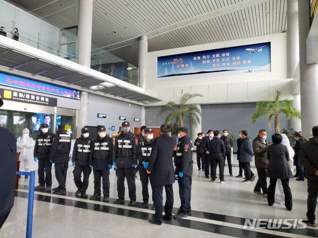  중국 산둥성 웨이하이국제공항에서 25일 방역요원들이 제주항공편으로 입국한 승객들을 버스에 태우고 있다.