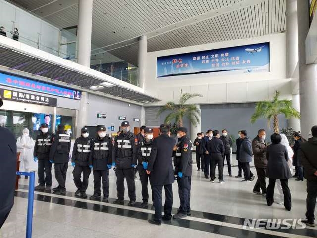 중국 산둥성 웨이하이국제공항에서 25일 방역요원들이 제주항공편으로 입국한 승객들을 버스에 태우고 있다.