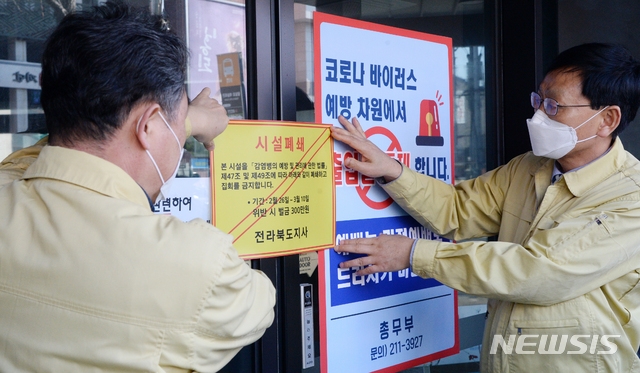 26일 전북 전주시 신천지 하늘문화센터에서 전라북도 관계자들이 '감염병 예방 및 관리에 관한 법률'의 행정명령을 집행해 시설을 폐쇄하고 스티커를 붙이고 있다. 