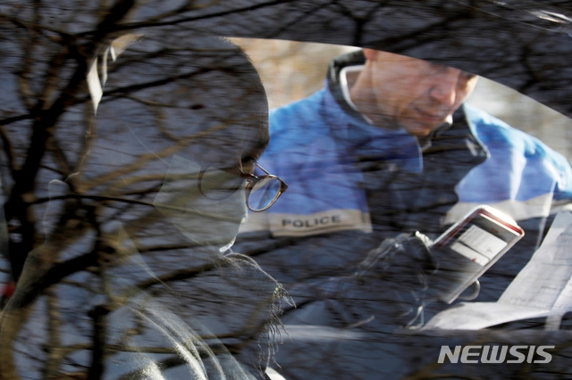 프랑스 파리 거리에서 한 경관이 자동차 를 검문하고 있다.