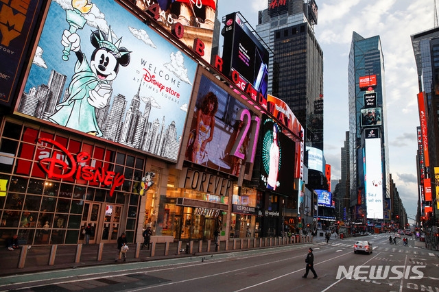 지난 20일(현지시간) 미국 뉴욕의 인적이 드문 타임 스퀘어 광장에서 한 경찰관이 7번가 도로를 건너고 있다.