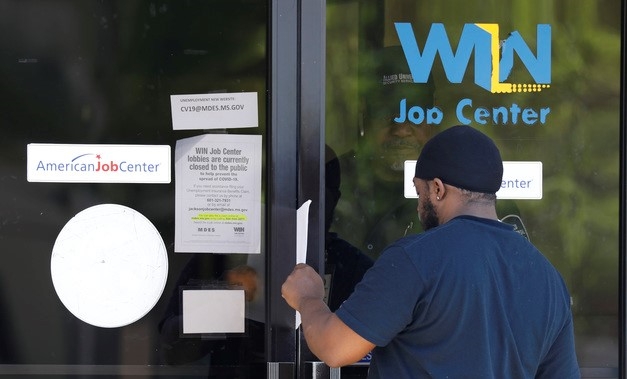  2일(현지시간) 미국 미시시피주 잭슨에 있는 주 직업 센터에서 타이론 키톤 주니어가 유리문 뒤에서 실업수당 청구 신청서를 건네받고 있다. 미 노동부는 3월 넷째주 신규 실업수당 청구 건수가 665만건을 기록했다고 밝혔다.
