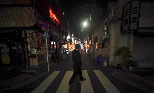 일본 정부가 신종 코로나바이러스 감염증(코로나19) 확산을 막기 위해 '긴급사태 선언'을 발령한 7일 밤 도쿄 신바시의 텅 빈 술집 거리를 한 시민이 걷고 있다.