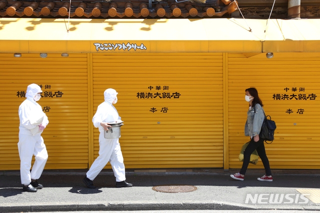 8일 일본 도쿄 인근 요코하마 차이나타운에서 신종 코로나바이러스 감염증(코로나19) 예방을 위해 보호복을 입은 식당 직원들이 걸어가고 있다.