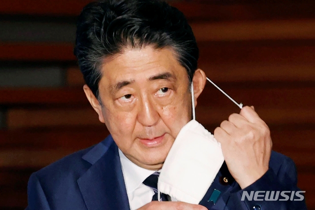 아베 신조 일본 총리가 21일 기자회견에서 마스크를 벗고 있다. 일본 정부는 이날 3개 지역에 대해 긴급사태 선언 추가 해제를 발표했다. 도쿄 등 5개 지역에 대해서는 오는 25일 다시 검토하겠다고 밝혔다.