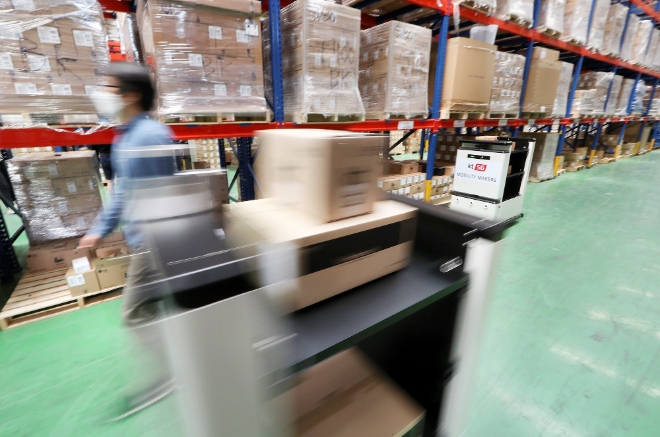 (사진=KT) KT 서부물류센터에 적용된 5G 자율주행 운반 카트가 관제실과 작업자의 요청에 따라 스마트폰 등 단말기를 지정된 화물 보관 위치로 자동 운반 하고 있다.