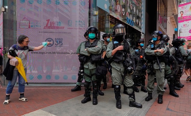 7일 홍콩 중심부에서 한 여성이 시위 진압 경찰이 경비중인 거리를 건너려 하고 있다. 중국 전국인민대표대회(전인대)가 처벌 대상을 대폭 확대하는 홍콩 국가보안법 수정안을 추진하는 가운데 홍콩 시위대는 입법부 청사 밖에서 이에 반대하는 시위를 벌이고 있다. 