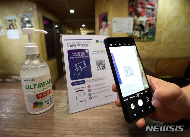 노래연습장과 클럽, 헌팅포차 등 고위험시설에 '전자출입명부'가 의무화된 10일 오후 서울 성동구의 한 노래연습장에서 시민이 QR코드를 찍고 있다. 전자출입명부 의무 도입 대상은 정부가 위험도 평가 결과 고위험 시설로 지정한 헌팅포차, 감성주점, 유흥주점, 단란주점, 콜라텍, 노래연습장, 줌바·태보·스피닝 등 실내집단운동, 실내 스탠딩공연장 등 8곳으로 오는 30일까지 계도 기간을 통해 미비 사항을 점검한다.