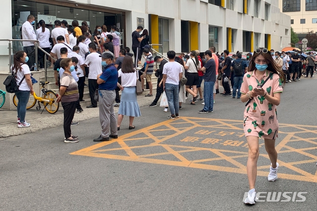최근 중국 베이징의 대형농수산물 시장에서 신종 코로나바이러스 감염증(코로나19) 집단 발병 사태 여파가 최소 3개 성으로 확산한 가운데 15일(현지시간) 베이징의 보건소 앞에서 핵산 증폭 검사를 받으려는 시민들이 마스크를 쓰고 줄 서 있다.