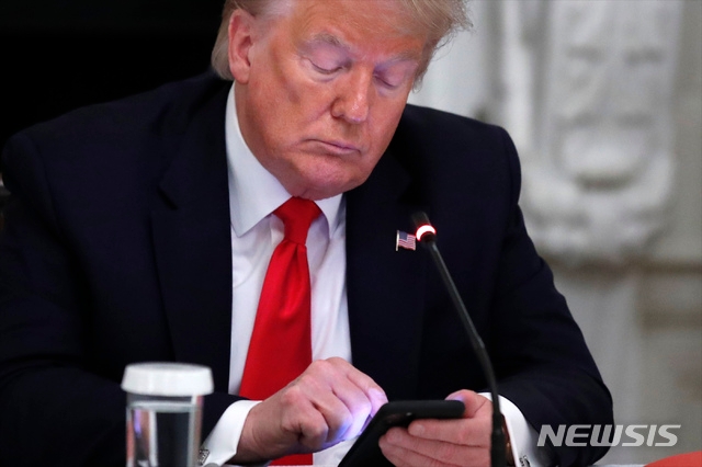 도널드 트럼프 대통령이 18일(현지시간) 백악관 다이닝룸에서 열린 미국 중소기업 재개장 관련 주지사들과의 원탁 회담에서 자신의 휴대전화기를 살펴보고 있다. 트럼프 대통령은 "볼턴이 북한과의 협상 당시 ‘리비아 모델’을 언급해 김정은이 분통을 터뜨렸다"며 "그때 그 자리에서 해고했어야 했다"라고 북미 관계 악화의 책임을 돌리는 트윗을 게재했다.