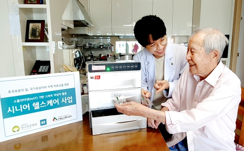 대구 보훈병원 방문간호사가 국가유공자 김갑생 씨의 자택에서 스마트 약상자를 이용해 복약 지도를 하고 있다. / 사진제공 = KT