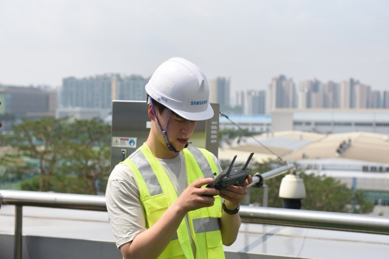삼성 5G 네트워크 성능 최적화 솔루션 개발자가 기지국과 안테나 각도 측정을 위해 원격에서 드론을 조종하고 있는 모습