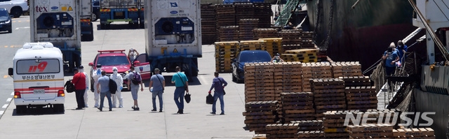 부산 감천항에 입항한 러시아 국적 냉동화물선 A호(3933t)의 선원 21명 중 16명이 신종 코로나바이러스 감염증(코로나19) 확진 판정을 받은 가운데 23일 오후 부산의료원으로 이송되는 확진 선원들이 A호에서 하선해 부산소방재난본부의 차량에 탑승하고 있다.