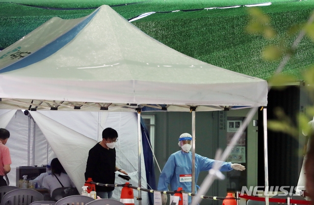 폭염이 이어지는 23일 오전 인천시 미추홀구보건소 신종 코로나바이러스 감염증(코로나19) 선별진료소에서 의료진이 검사를 받으러 온 시민을 안내하고 있다.