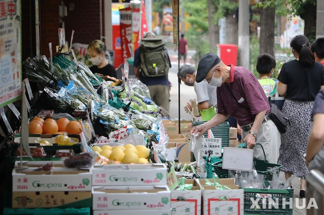 지난달 27일 일본 도쿄의 한 가게에서 마스크를 착용한 사람들이 과일과 채소를 고르고 있다.