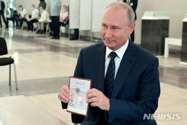 블라디미르 푸틴 러시아 대통령이 1일(현지시간) 러시아 모스크바의 한 투표소에 도착해 신원 확인을 위해 선거관리위원회 관계자에게 여권을 보여주고 있다. 이날 러시아에서 푸틴 대통령의 장기집권을 터줄 헌법 개정 국민투표 본 투표가 열렸다. 