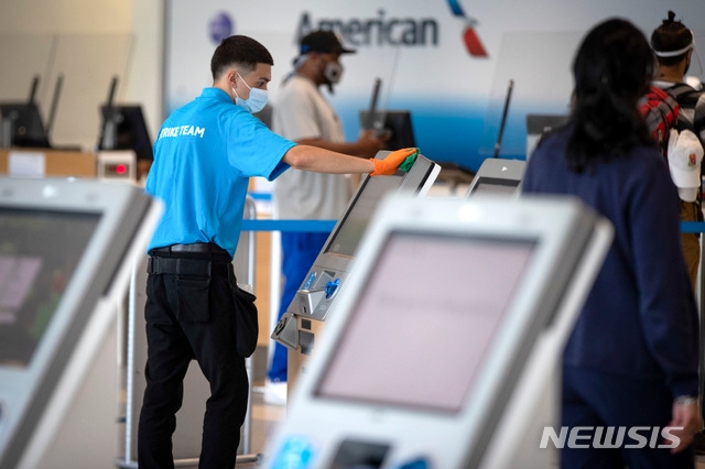 6월30일(현지시간) 미국 텍사스주 그레이프바인에 위치한 댈러스 포트워스 국제공항에서 직원들이 아메리칸 항공 체크인 키오스크(무인기기)를 닦고 있다.