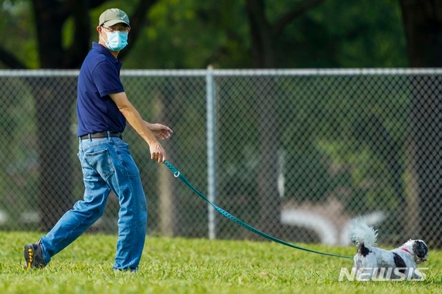 지난 2일 텍사스 리처드슨에서 한 남성이 마스크를 착용한 채 강아지를 산책시키고 있다. 통계 사이트 월드오미터에 따르면 6일(현지시간) 기준 미국 내 신종 코로나바이러스 감염증(코로나19) 누적 확진자는 300만명을 넘어섰다.