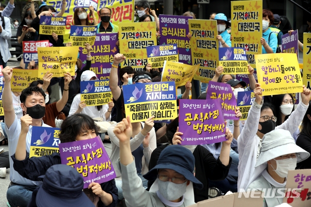 정의기억연대와 참석자들이 지난 1일 서울 종로구 옛 일본대사관 앞에서 28년 동안 열리던 소녀상 옆이 아닌 인근으로 자리를 옮겨 일본군 위안부 문제 해결 촉구 정기 수요시위를 열고 구호를 외치고 있다.