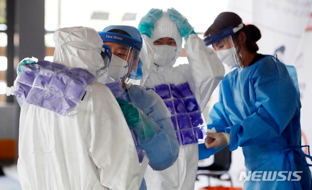 8일 광주 북구보건소 효죽공영주차장 코로나19 선별진료소에서 의료진들이 더위를 이겨내기 위해 서로에게 냉조끼를 입혀주고 있다. (사진 = 광주 북구 제공)