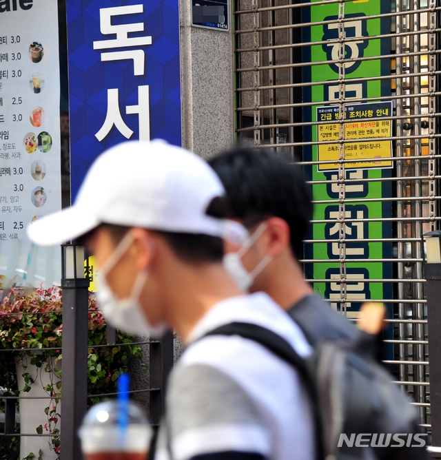 광주의 한 고시학원에서 7명이 신종 코로나바이러스 감염증(코로나19) 확진 판정을 받은 가운데 학원생들이 마스크를 착용하고 8일 오전 동구 대의동 폐쇄된 학원 앞을 지나가고 있다.