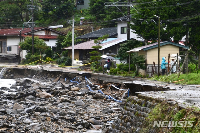 10일 일본 기후현 다카야마에서 주민들이 호우로 유실된 도로를 걷고 있다. 일본 일부 지역에서 실종자 수색 작업과 복구 작업이 이어지는 가운데 관계 당국은 이번 주말 더 많은 비가 내릴 것에 대비하고 있다.