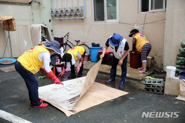 대한적십자사 부산지사 자원봉사원과 직원 등이 11일 집중호우로 인해 부산 동구와 부산진구를 걸쳐 흐르는 도심 하천인 '동천'의 범람으로 침수피해를 입은 자성대아파트에서 청소, 세탁 등 긴급구호활동을 실시하고 있다. (사진=부산적십자 제공).