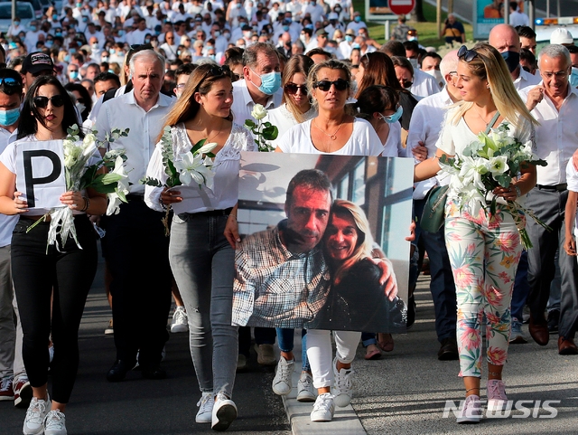 프랑스 남서부도시 바욘에서 코로나19 방역 수칙에 따라 승객들에게 마스크착용을 권하다가 몰매를 맞아 숨진 필립 몽기요씨의 아내 베로니크(가운데)가 8일 남편의 사진을 들고 시위대와 함께 엄정한 처벌을 요구하고 있다.