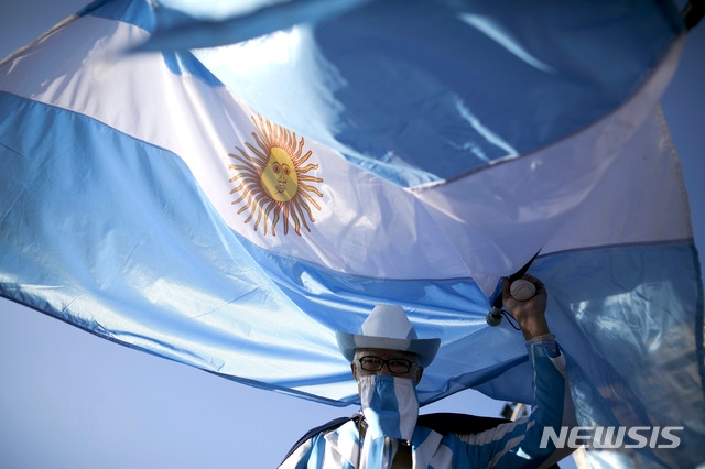 독립기념일인 9일(현지시간) 부에노스아이레스에서 정부의 코로나19 봉쇄 해제를 요구하는 시위가 열려 대형 국기를 든 한 남성이 시위대와 행진하고 있다. 독립기념일 연휴 동안 전국에서 시민들이 알베르토 페르난데스 대통령의 코로나19 봉쇄 해제를 요구하는 시위가 열렸다.