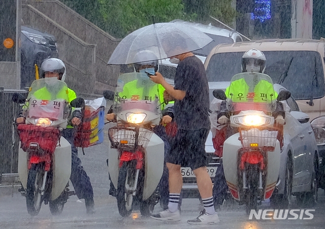 전국 곳곳에 비가 내린 지난 13일 오후 인천시 서구청 근처 도로에서 우체국 집배원이 우편물 배달을 위해 빗속을 달리고 있다.